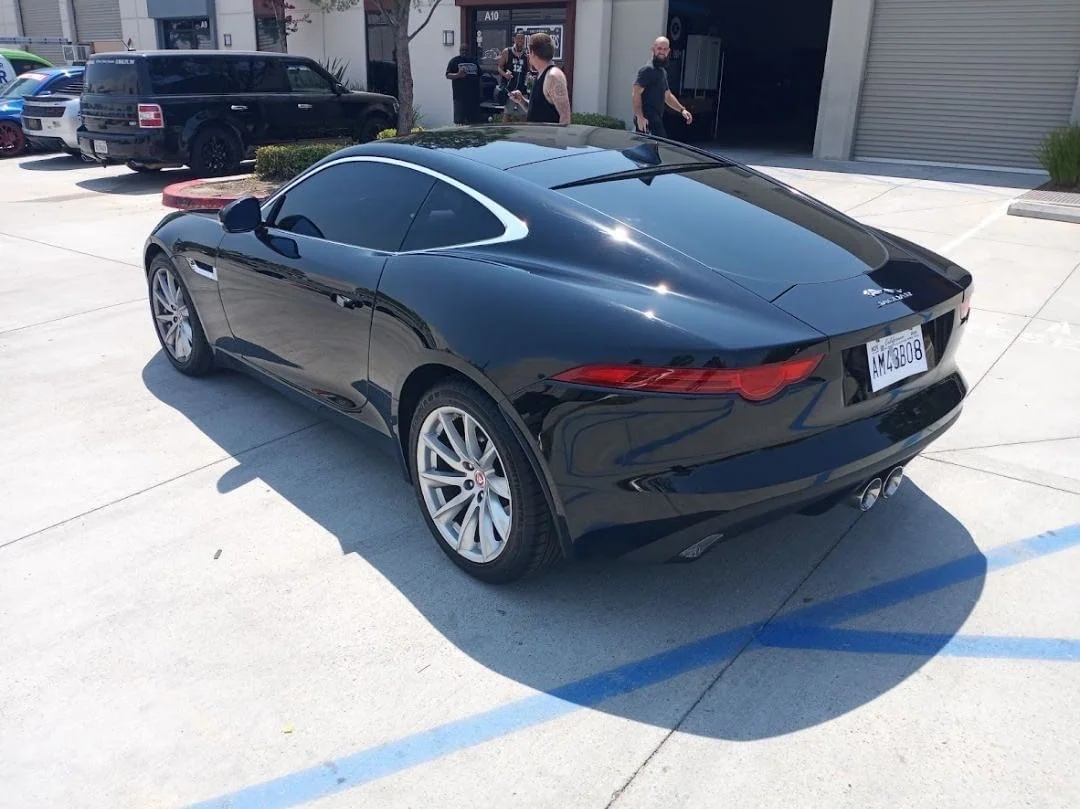 Black luxury coupe with professionally installed dark window tint in commercial lot