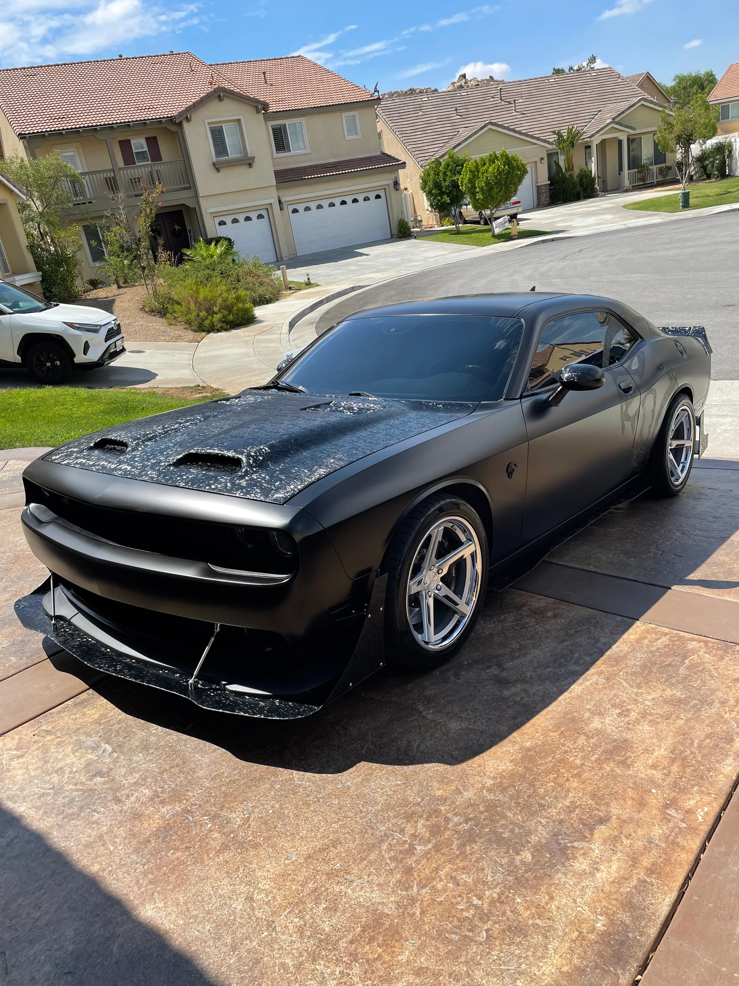 Black Dodge Challenger with professional window tint installed in residential driveway