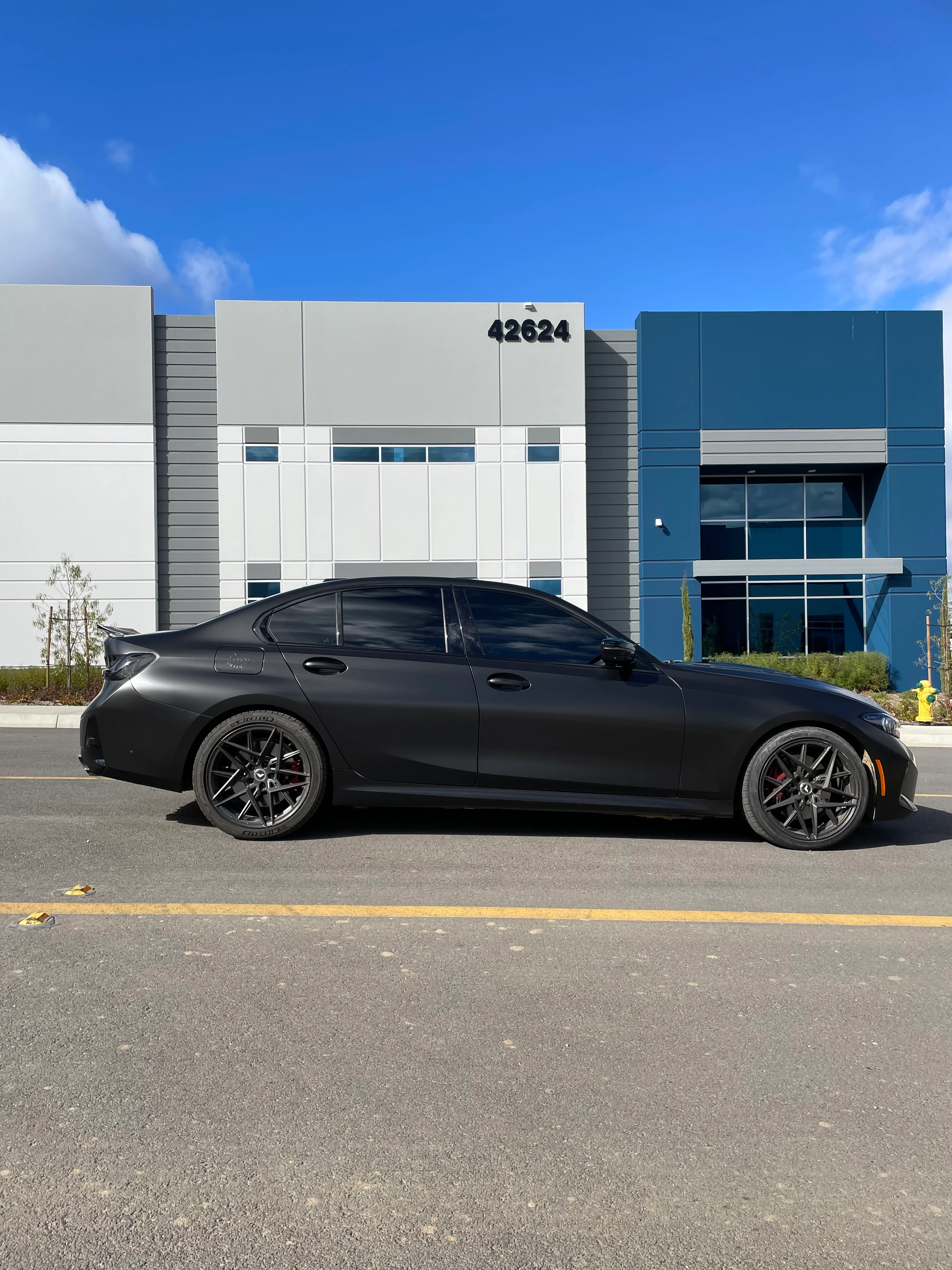 Black sedan with professional window tint installed, parked in front of modern commercial building