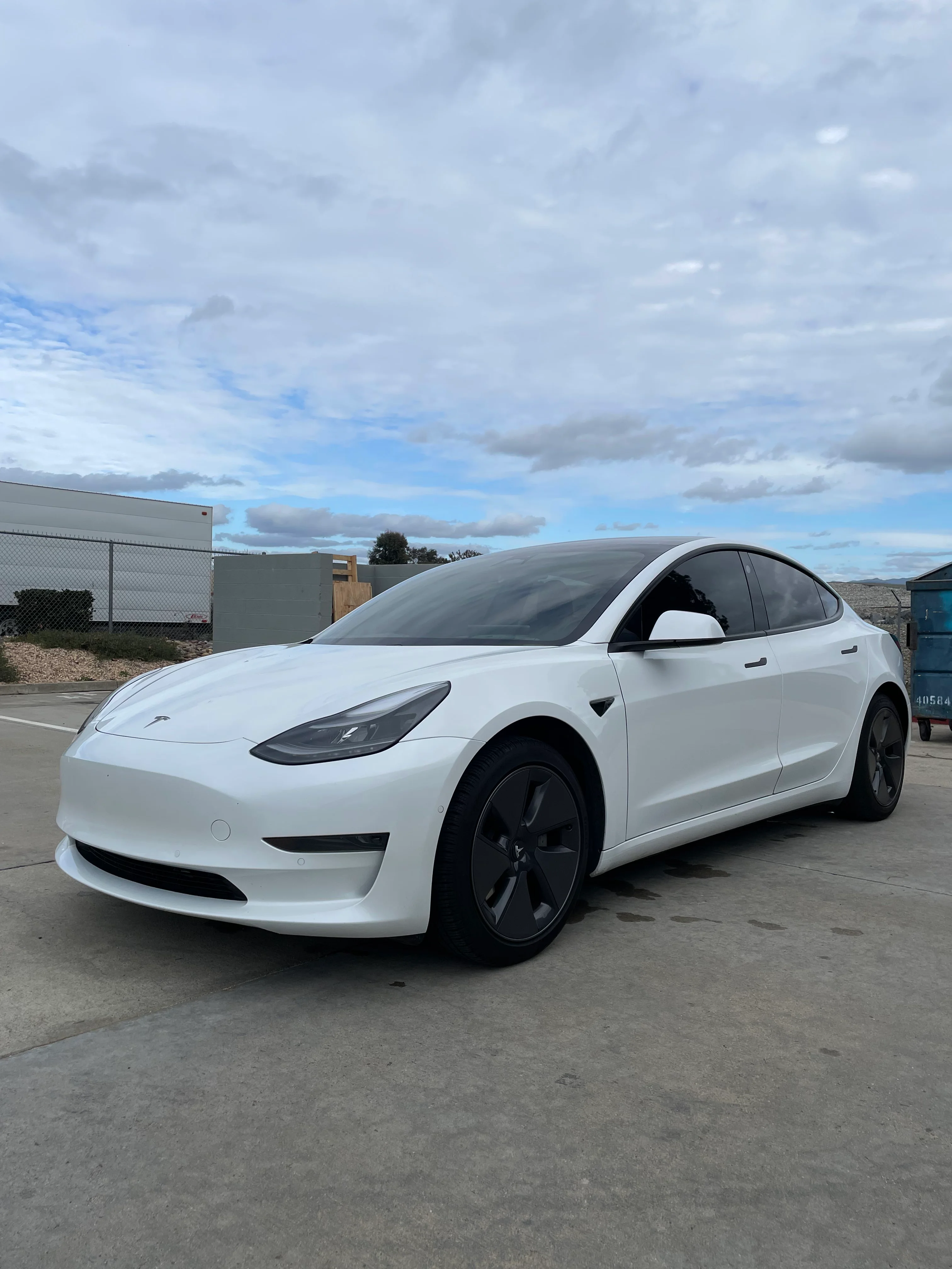 White Tesla Model 3 with dark window tint installed on all windows, parked in lot