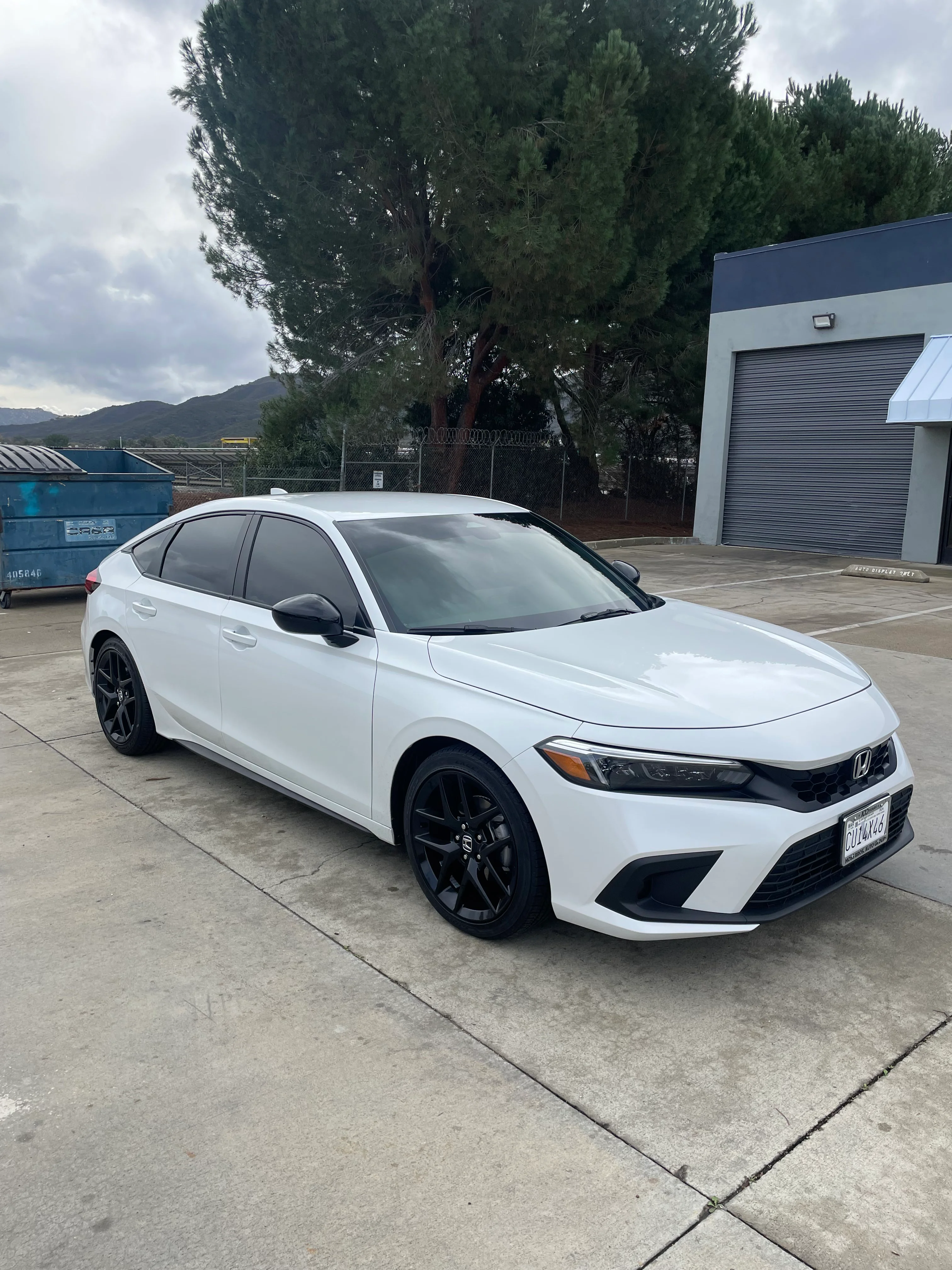 White Honda Civic with dark window tint applied to all windows, parked on concrete