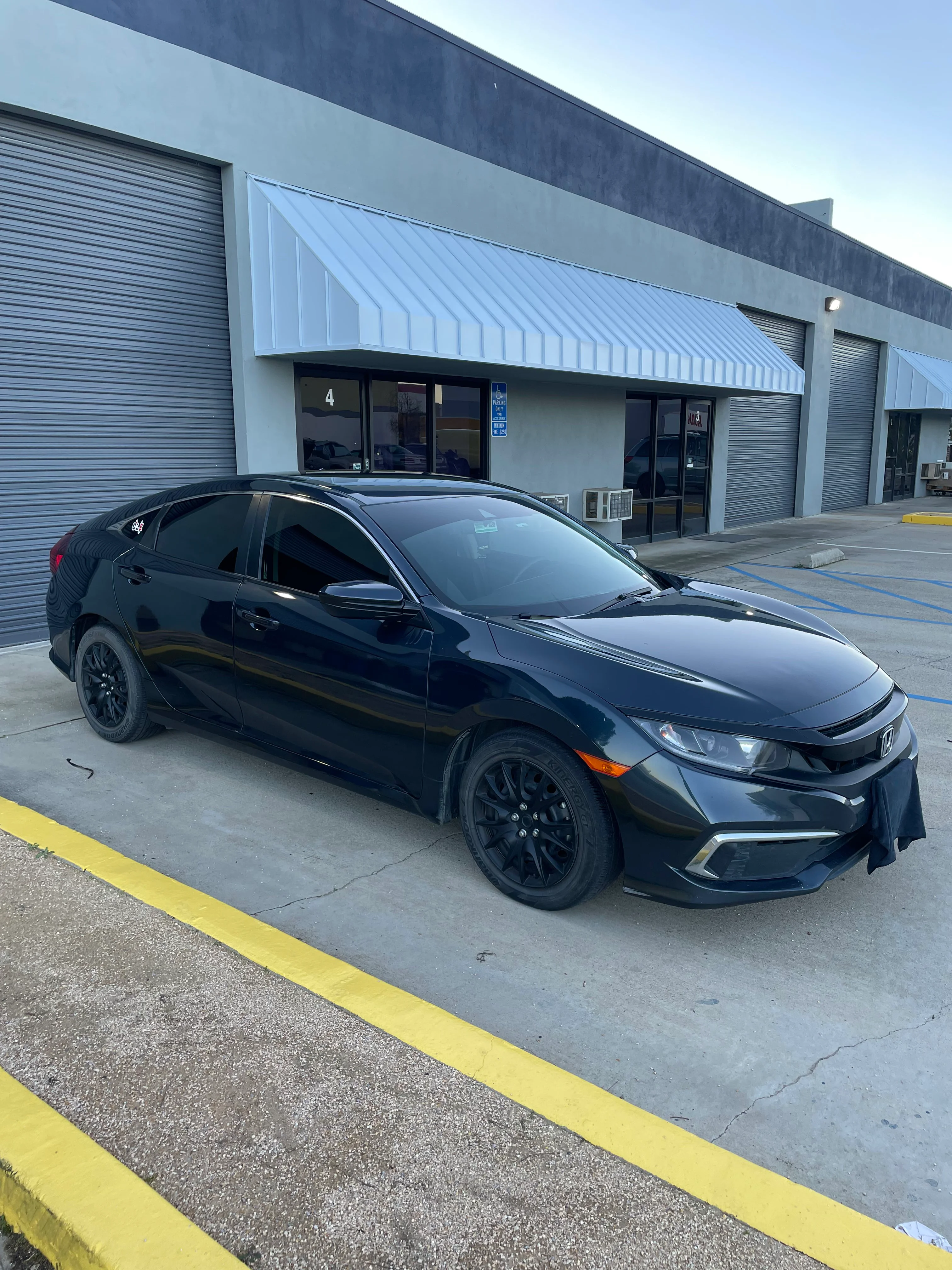 Black Honda Civic with professional window tint installed at commercial location