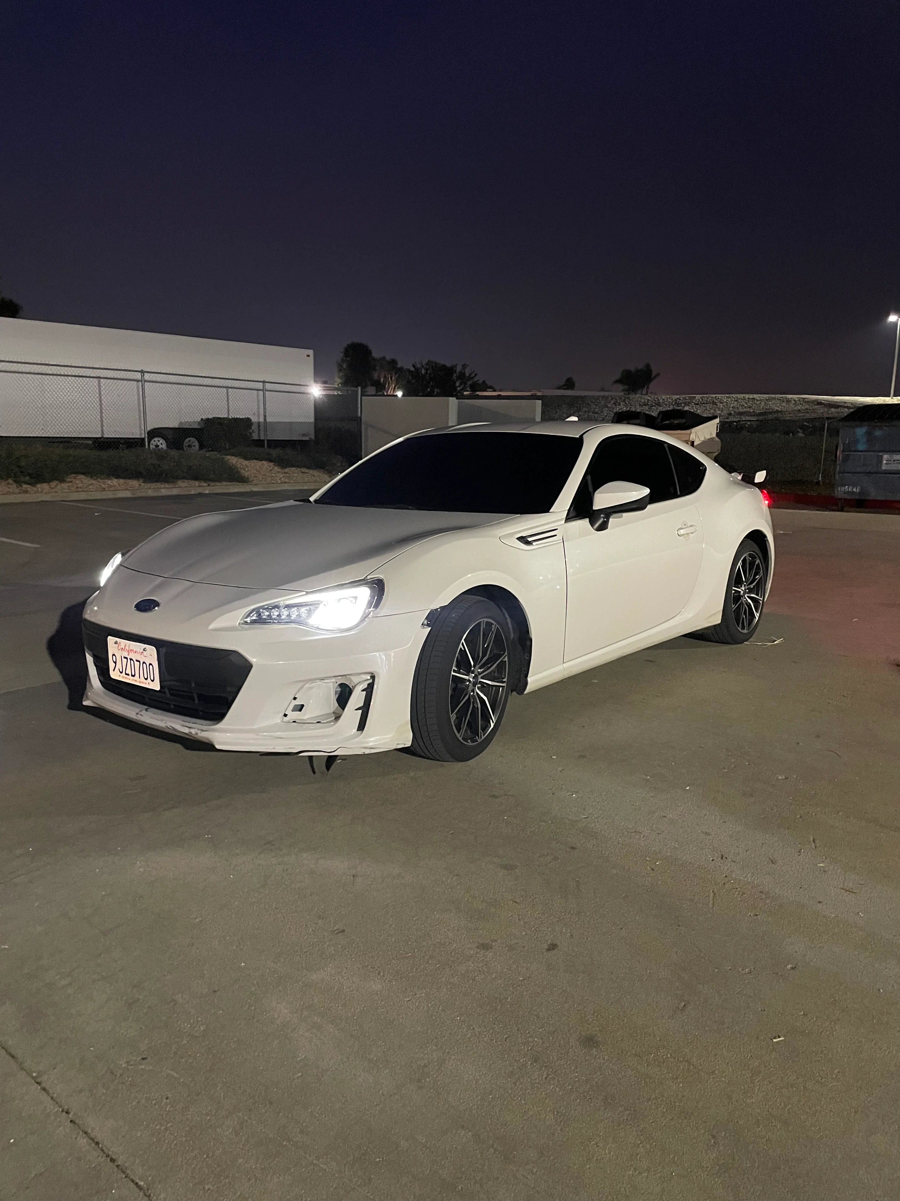 White Subaru BRZ with dark window tint applied, parked in lot at dusk