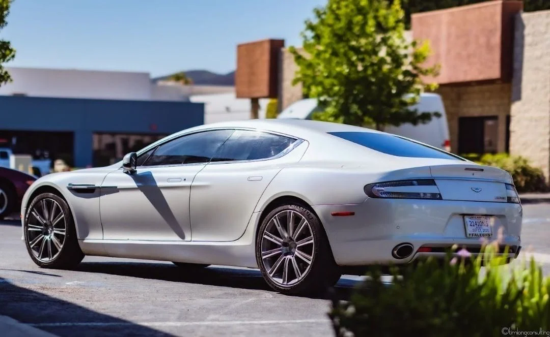 Silver Aston Martin with dark window tint in commercial parking lot